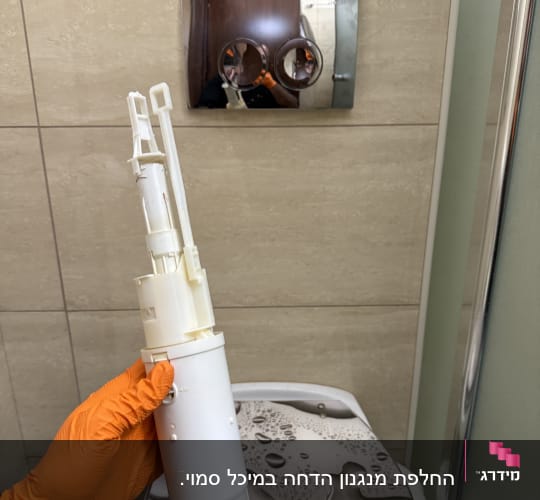 יד עם כפפה כתומה מחזיקה חלק של אסלה